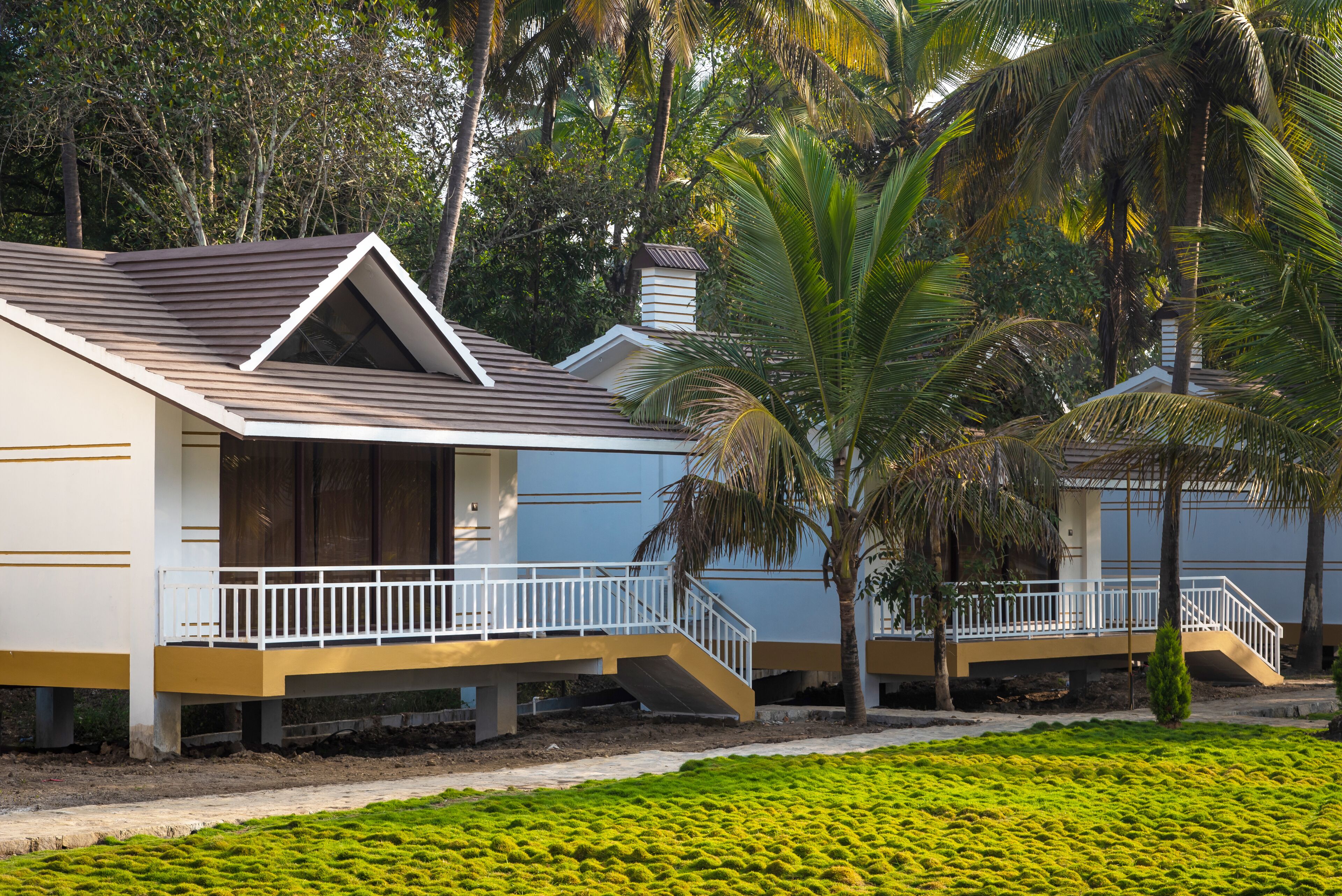 Un bungalow moderno con balcón, rodeado de exuberante follaje y palmeras.
