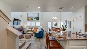 Una cocina amplia con comedor, piso de madera y un cuadro grande sobre la mesa.