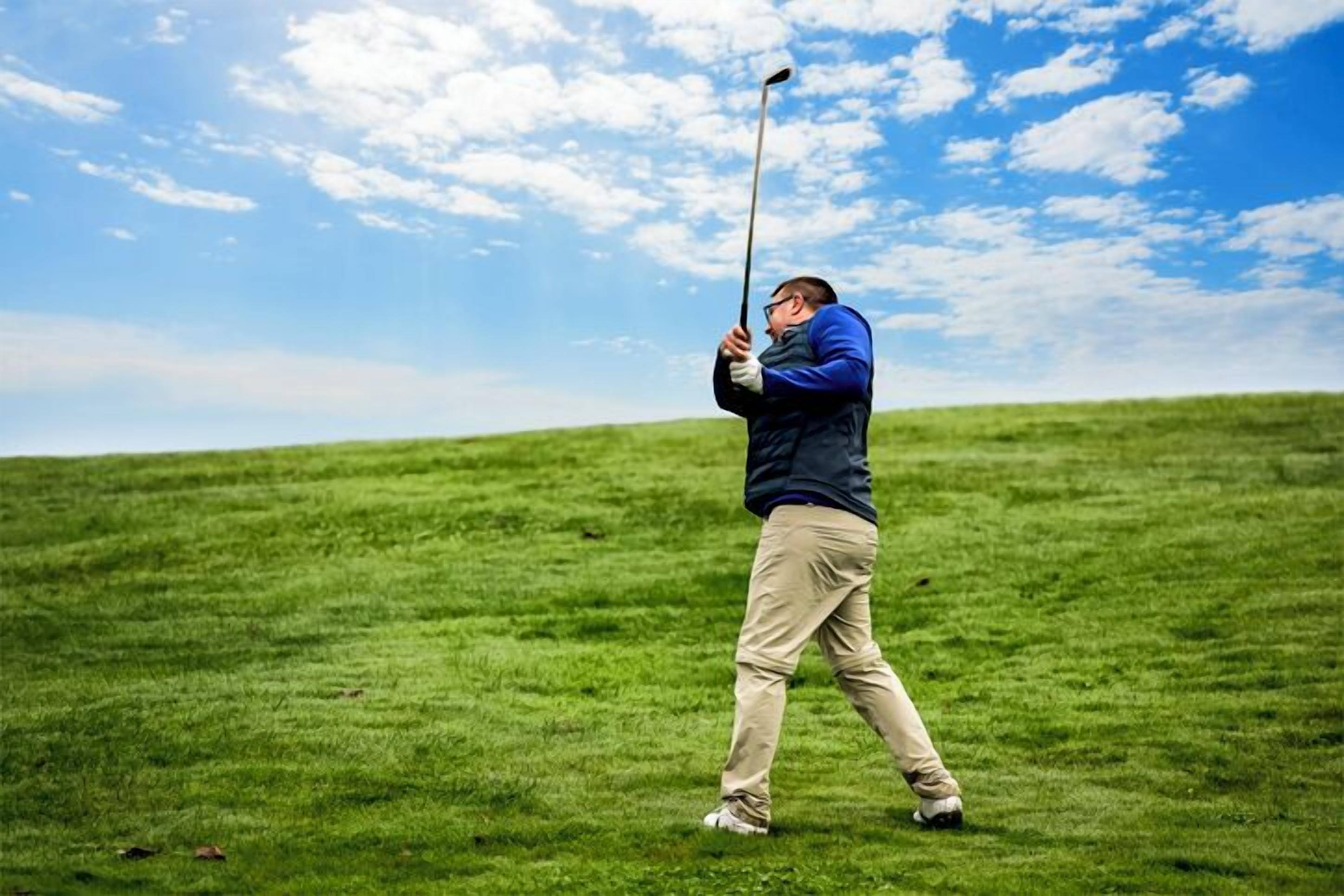 Una persona juega al golf en un campo cubierto de hierba bajo un cielo despejado.