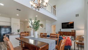 Una cocina amplia con comedor, una sala de estar con televisor y una escalera a un nivel superior.