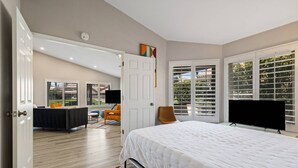 Quarto com cama grande, televisão e janela com persianas.