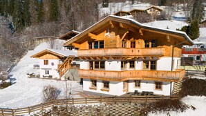 Een chalet van hout met meerdere verdiepingen en een balkon, gelegen op een besneeuwde helling.