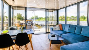 Een modern interieur met een groot raam, een blauwe bank, een houten tafel en een eethoek.