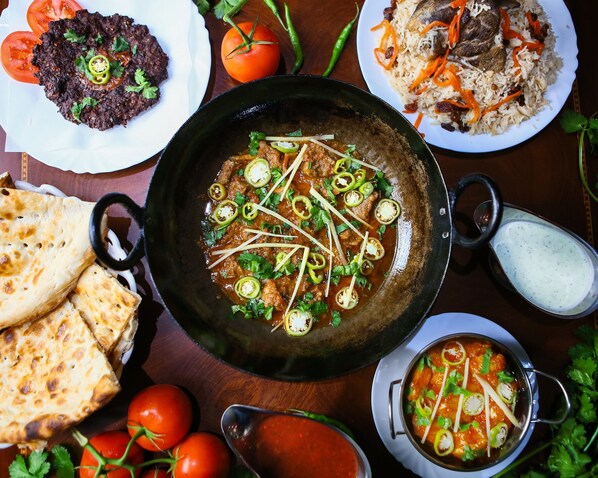 A variety of dishes including a bowl of curry, flatbread, and rice with vegetables. - Fort Continental Hotel (Peshawar)