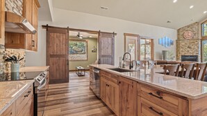 A spacious kitchen with wooden cabinets, a large island, and a stone backsplash. - Zion Cabin Retreat - Luxury with Nature Trails in Uncrowded East Zion. 3 kings (Orderville)
