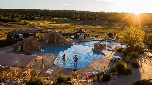 A swimming pool with lounge chairs and a gazebo, surrounded by natural landscape and a clear sky. - Zion Cabin Retreat - Luxury with Nature Trails in Uncrowded East Zion. 3 kings (Orderville)