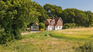 A rural house with a large garden and a small adjacent structure.