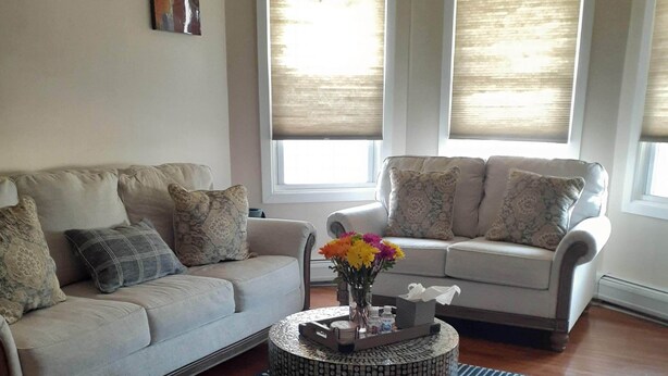 A living room with two sofas, a coffee table, and a patterned rug. - Apt with utilities, wifi, a compact parking space, & on-site laundry near NYC! (Bayonne)