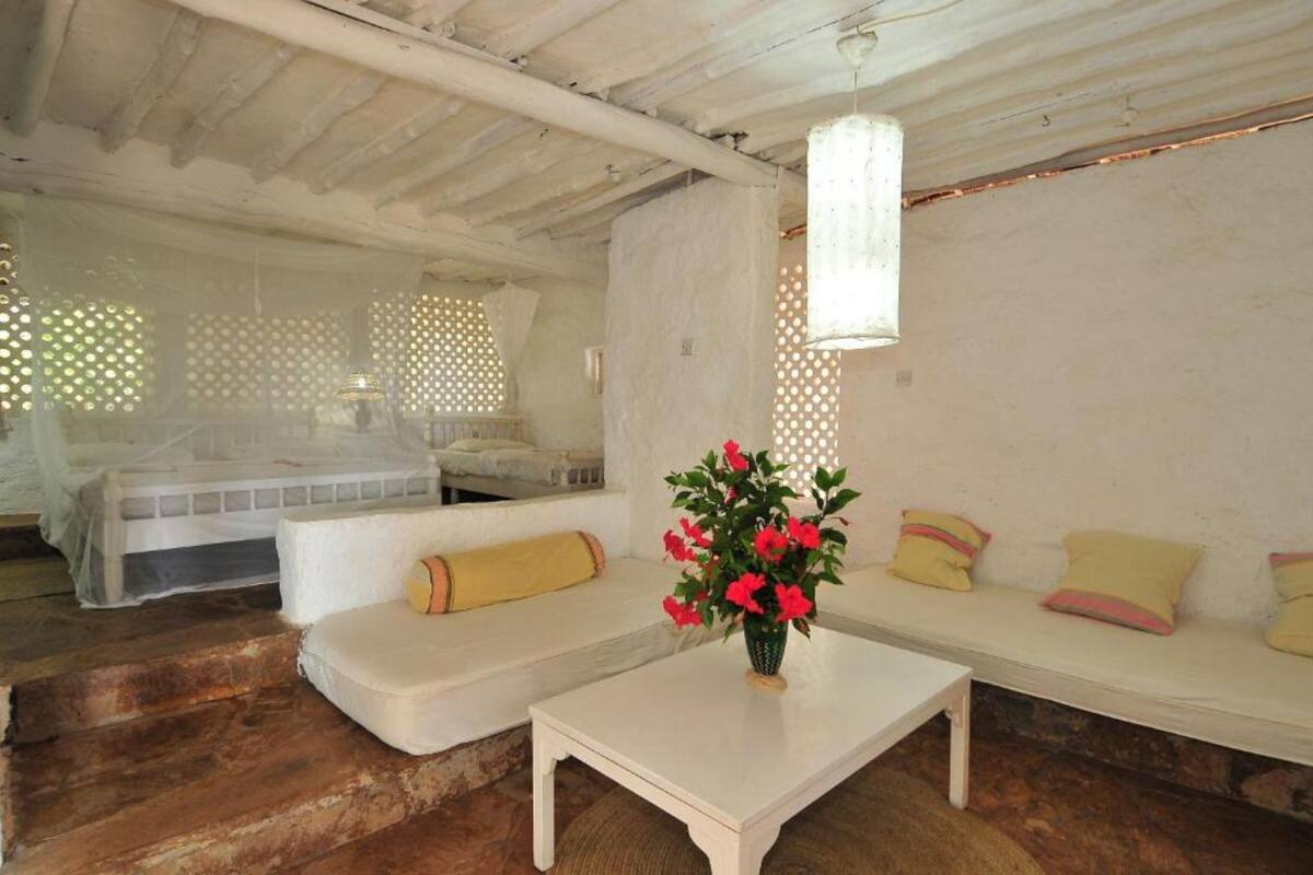 A cozy room with a white sofa, a small table with a vase of flowers, and a bed with a white canopy.