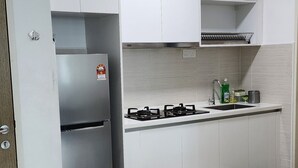 Una cucina moderna con mobili bianchi, un frigorifero in acciaio inossidabile, un piano cottura a gas e una parete rivestita di piastrelle.