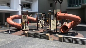 Un cortile con una bicicletta, un cartello con delle lettere e una scultura di tubi.