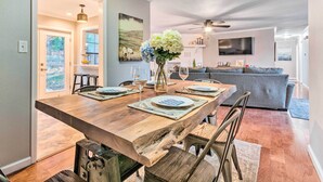Un comedor con una mesa de madera dispuesta para cuatro personas, un florero con flores y vista al salón.