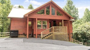 Een houten chalet met schuin dak, een veranda en een trap naar de ingang.