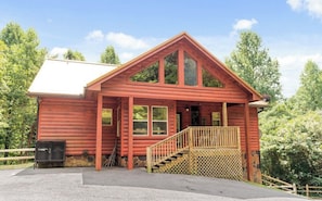 A wooden cabin with a sloped roof, a front porch, and a staircase leading to the entrance.