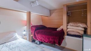 Un dormitorio compacto con una cama individual, una mesita de noche pequeña y un armario empotrado.