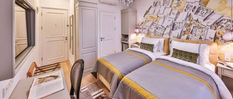 A hotel room with two beds, a desk, and a chandelier.