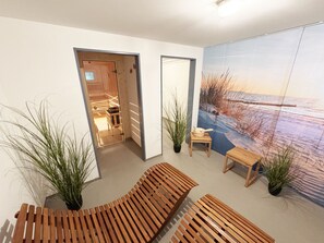 Ein modernes Interieur mit Holzbänken, Topfpflanzen und einem großen Wandbild mit Strandmotiv.