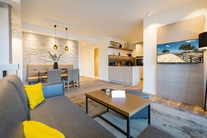 A modern living room with a grey sofa, yellow cushions, a wooden coffee table, and a stone accent wall. - Beachhouse Bansin, app. 09 (Heringsdorf)