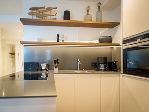 Una cocina moderna con encimera de acero inoxidable, cafetera y horno Siemens.