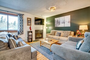A cozy living room with a fireplace, a sofa, a coffee table, and a view of the outdoors. - Walk to Main St: Recently Renovated Frisco Condo (Frisco)