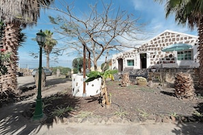 A stone building with a white facade, a palm tree, and a street lamp.