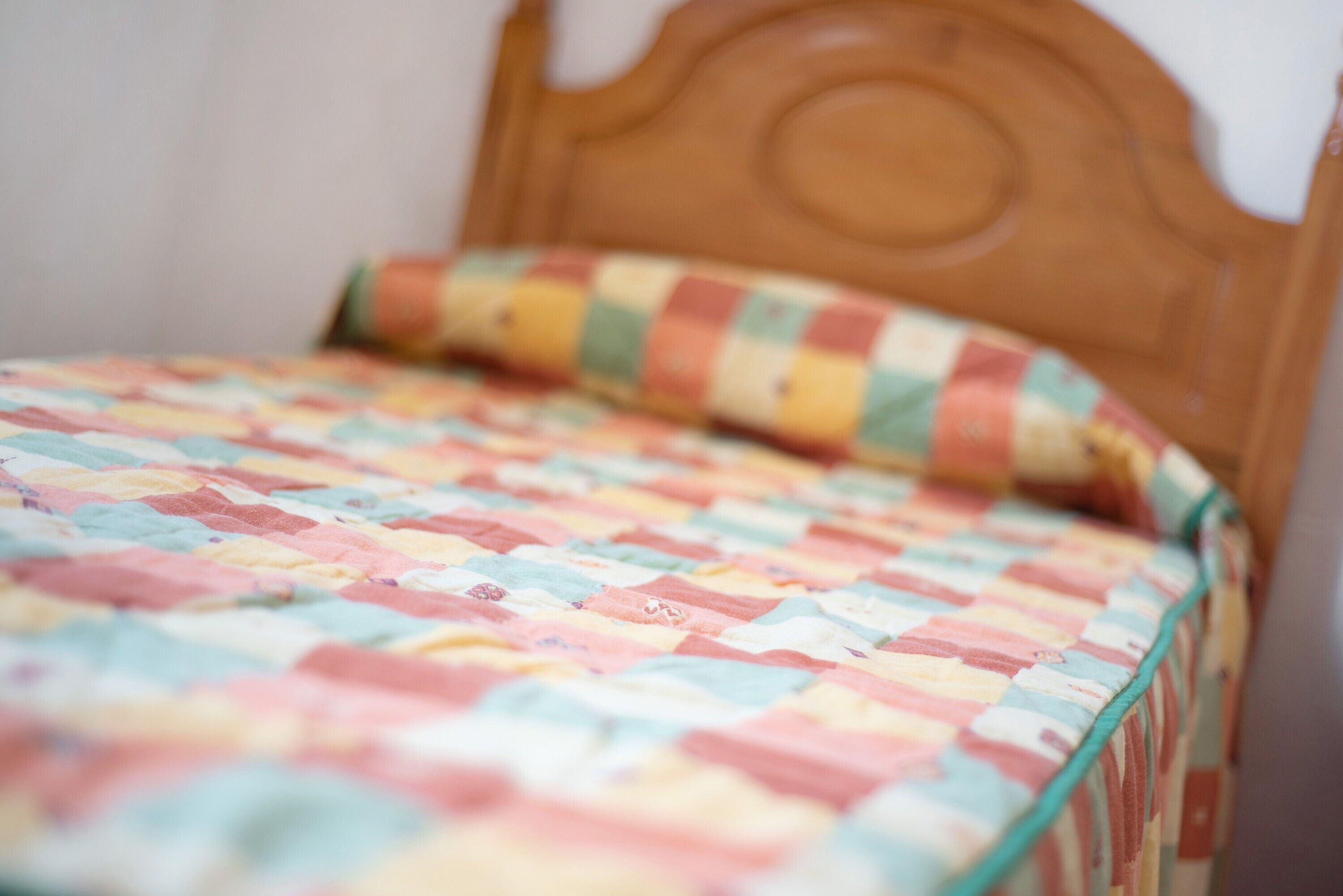 Een bed met een kleurrijke quilt en een houten hoofdbord.