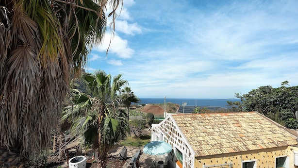 Ein Haus mit Ziegeldach, einer Terrasse mit Tisch und Stühlen und Blick auf den Ozean.