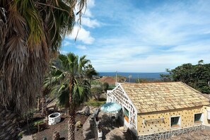 Ein Haus mit Ziegeldach, einer Terrasse mit Tisch und Stühlen und Blick auf den Ozean.