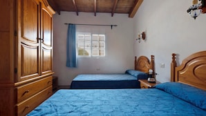Ein Schlafzimmer mit zwei Betten, einem Holzschrank und einem Fenster mit Vorhängen.
