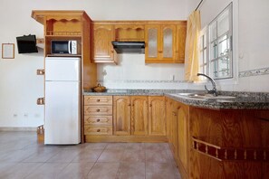 Une cuisine avec des meubles de rangement en bois, un four à micro-ondes, une cuisinière et un réfrigérateur.