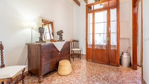 A room with a wooden dresser, a chair, a lamp, a mirror, and a door with glass panels. - Holiday Home 'Ca Na Francesca' with Mountain View, Wi-Fi and Air Conditioning (Pollença)