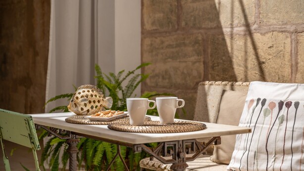 A table with a plate of food, two white cups, and a decorative fish. - Holiday Home 'Ca Na Francesca' with Mountain View, Wi-Fi and Air Conditioning (Pollença)