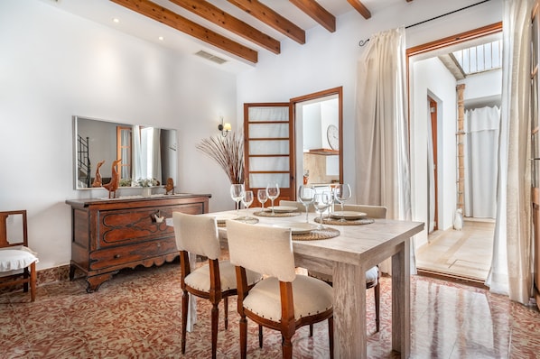 Un comedor con una mesa de madera dispuesta para cuatro, un aparador de madera y un espejo en la pared.
