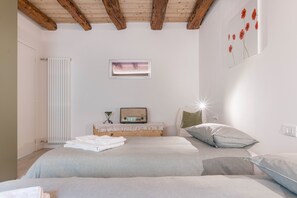 Ein Schlafzimmer mit zwei Betten, einem Heizkörper, einem gerahmten Bild, einem Radio und einer Wandleuchte.