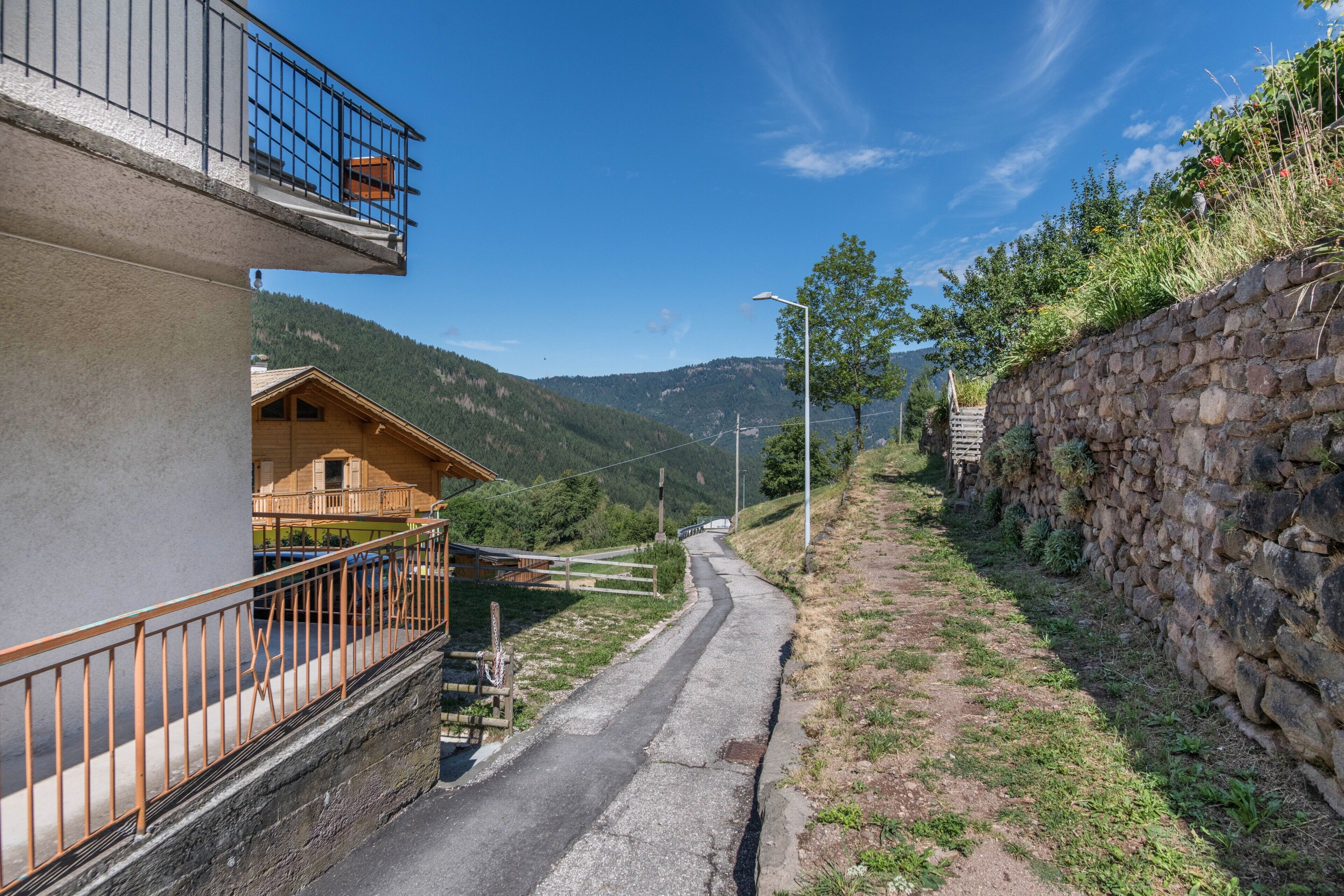 Une rue étroite bordée de murs de pierre et de bâtiments en bois dotés de balcons.