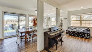 Un salón espacioso con un piano, una mesa de comedor con sillas y un amplio ventanal con vistas al exterior.