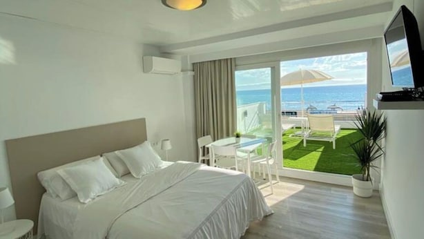 A hotel room with a bed, a TV, a balcony with a view of the sea, and a small table with chairs. - Apartment Sea View Terrace (Torremolinos)
