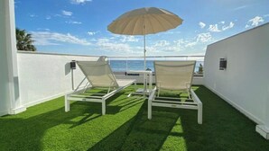 Two lounge chairs with a canopy umbrella on a rooftop terrace with a view of the ocean. - Apartment Sea View Terrace (Torremolinos)