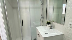 A modern bathroom with a glass shower enclosure, a white sink, and a small potted plant. - Apartment Sea View Terrace (Torremolinos)