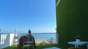 A balcony with a table and chairs, overlooking a clear blue sky and a distant view of the sea. - Apartment Sea View Terrace (Torremolinos)