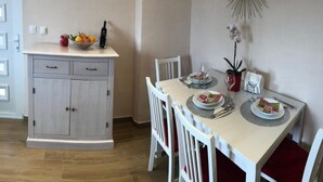 A dining area with a white table set for two, a grey cabinet with drawers, and a wall-mounted mirror. - Sunone Dubrovnik (Dubrovnik)