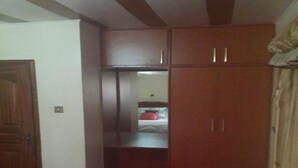 Habitació amb un armari de fusta, un llit i una catifa vermella.