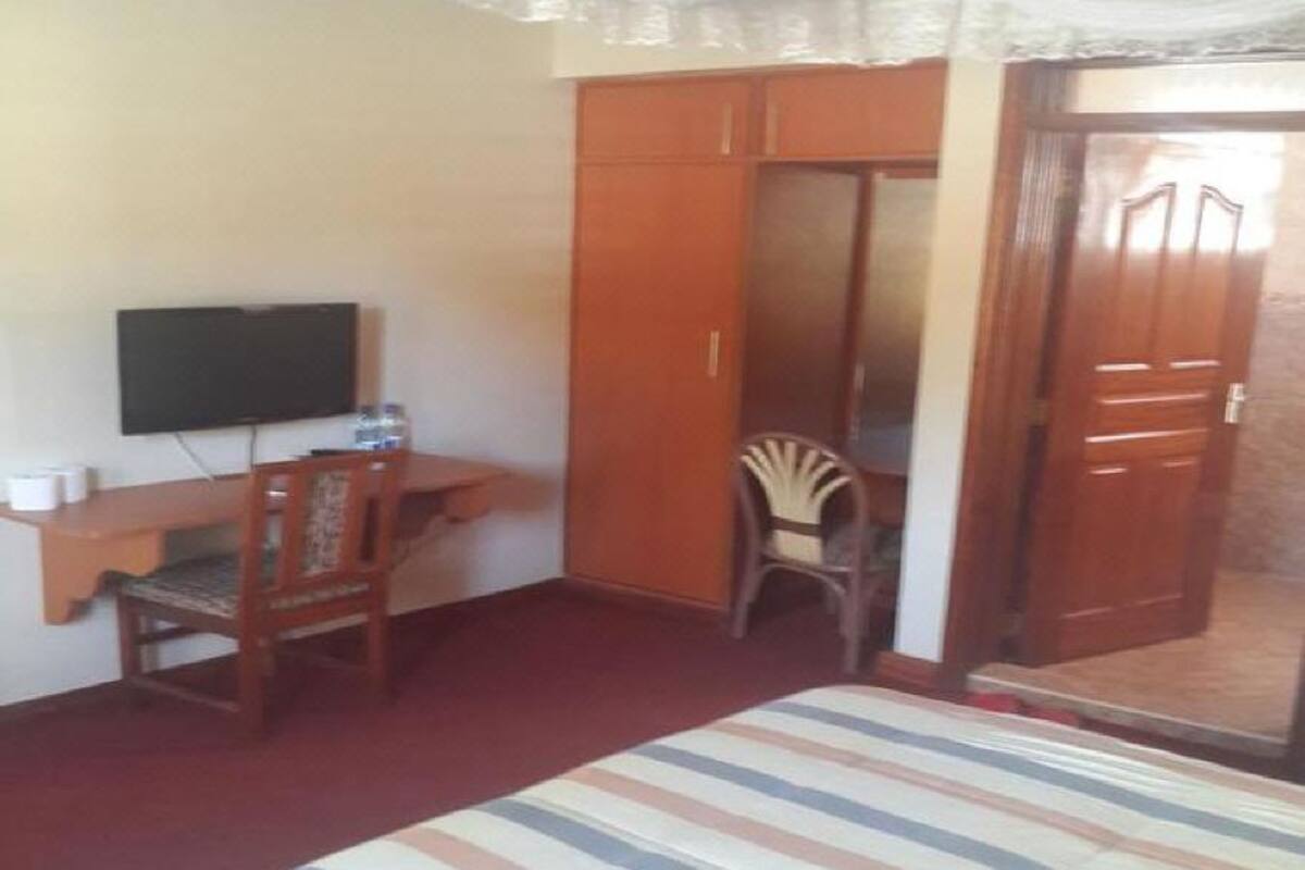 Un dormitorio con cama, escritorio, silla, televisor y armario.