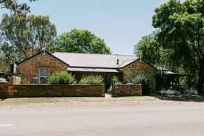 A stone building with a metal roof, surrounded by trees and a stone wall. - Unwind in Our Cosy 2 BR Spa Cottage with Log Fire. Mintaro Hideaway Carpenter (Mintaro)