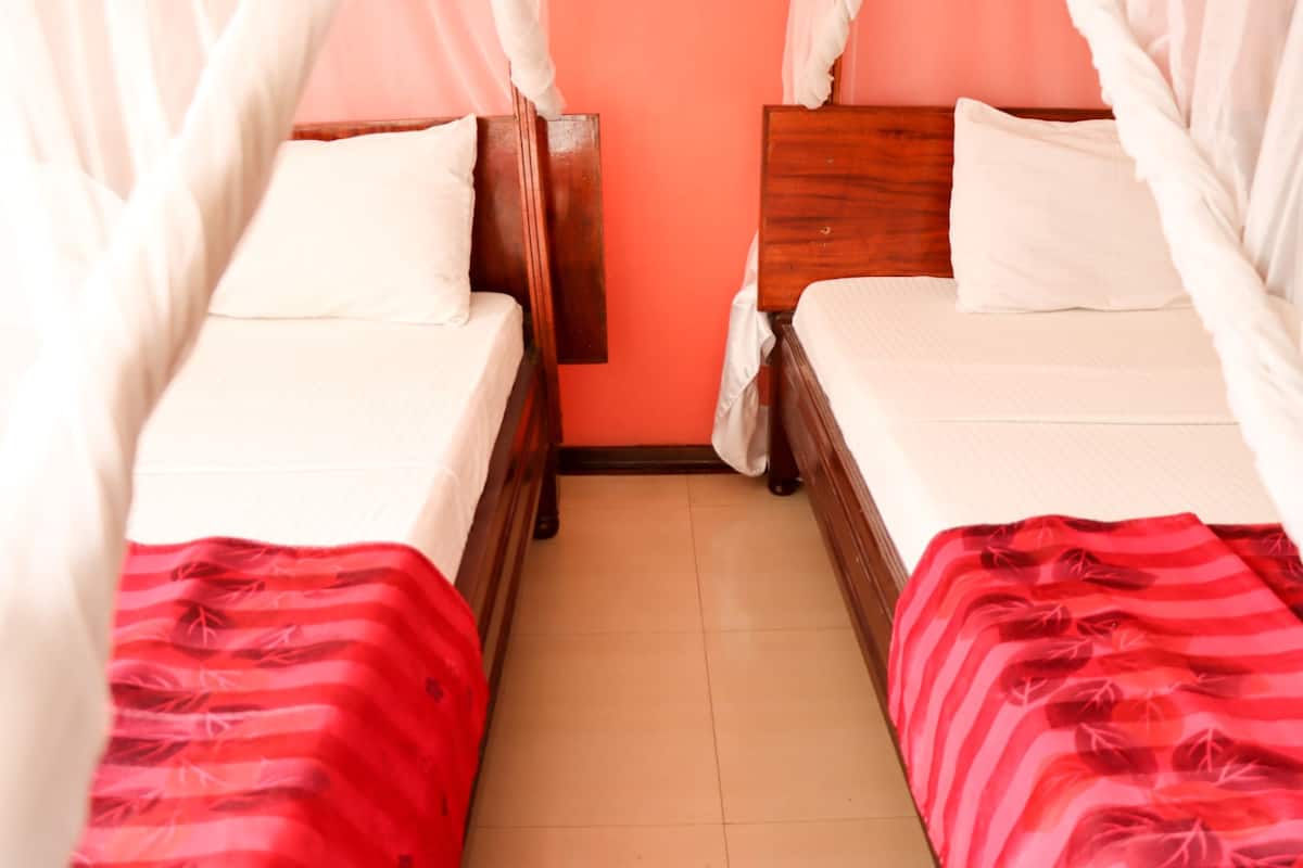 Una habitación con dos camas, cada una con cabecero de madera y ropa de cama blanca.