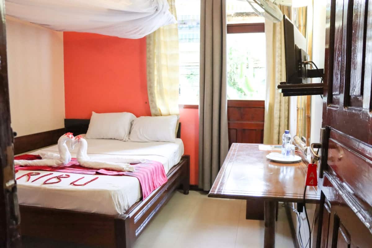 Una habitación de hotel con cama, mesa y ventana.