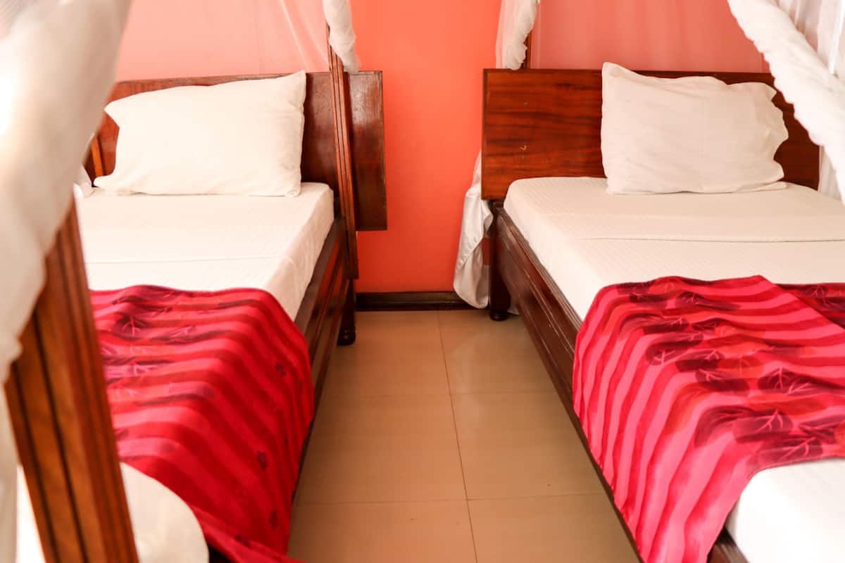 Una habitación con dos camas de madera, cada una con almohadas blancas y colchas a rayas rojas.