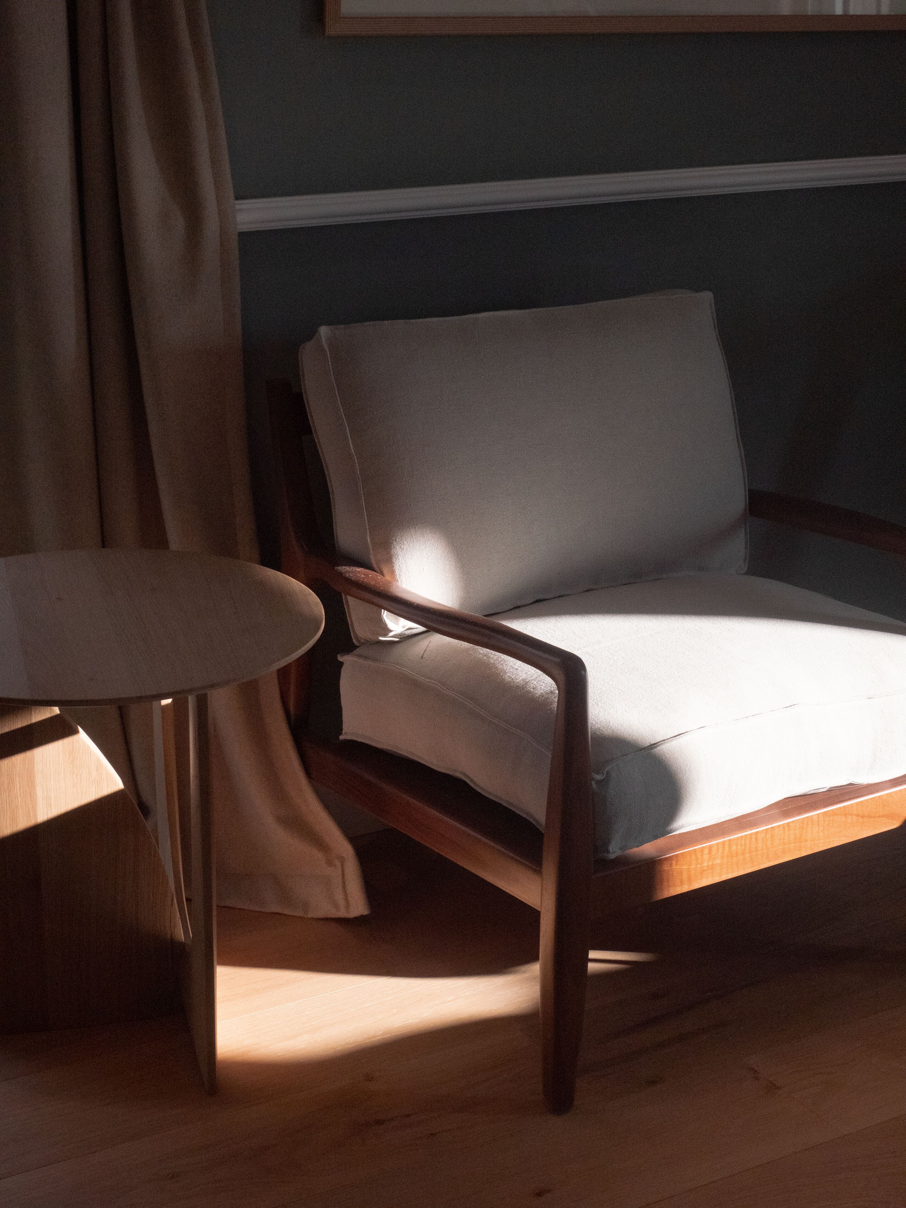 Una habitación con una silla de madera y una mesita.