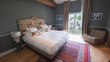 Un dormitorio moderno con una cama grande, una lámpara de pie verde, un tapete estampado y vistas al exterior a través de una puerta corrediza de vidrio.