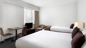 Une chambre d’hôtel avec un grand lit, un bureau avec une chaise, une télévision et deux fauteuils.
